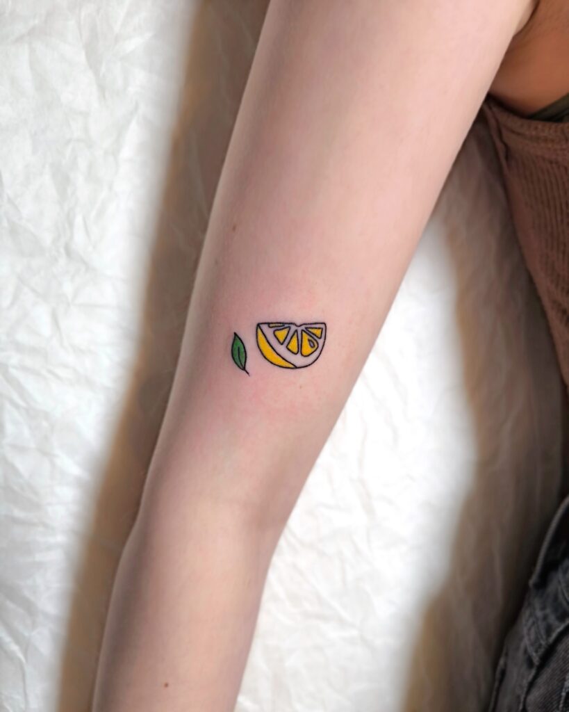 Handpoke Lemon Tattoo with a small green leaf tattoo