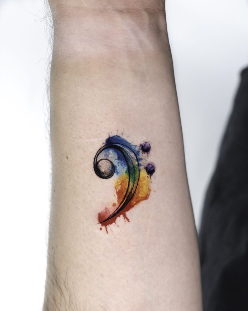 Watercolor Bass Clef Tattoo which has rainbow colors in watercolor effect.