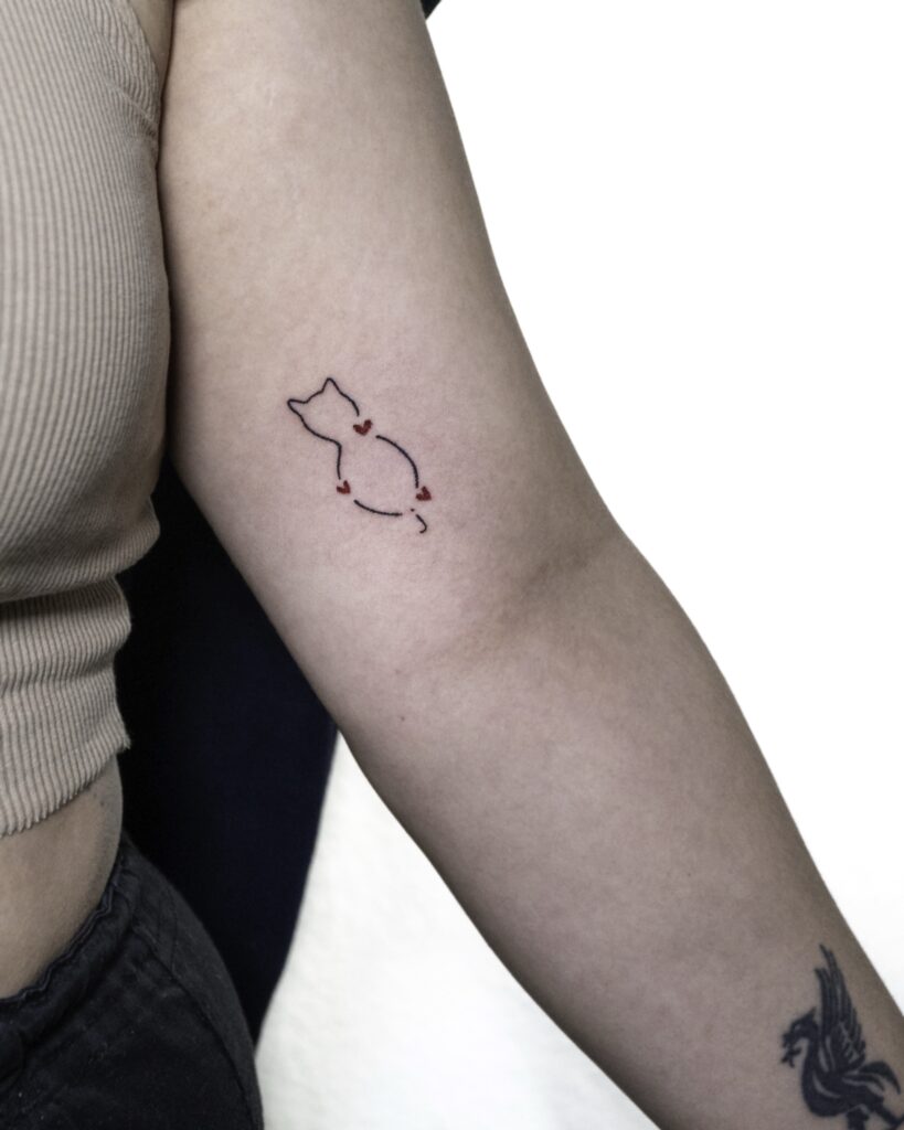 A cat figure tattoo with little red hearts.