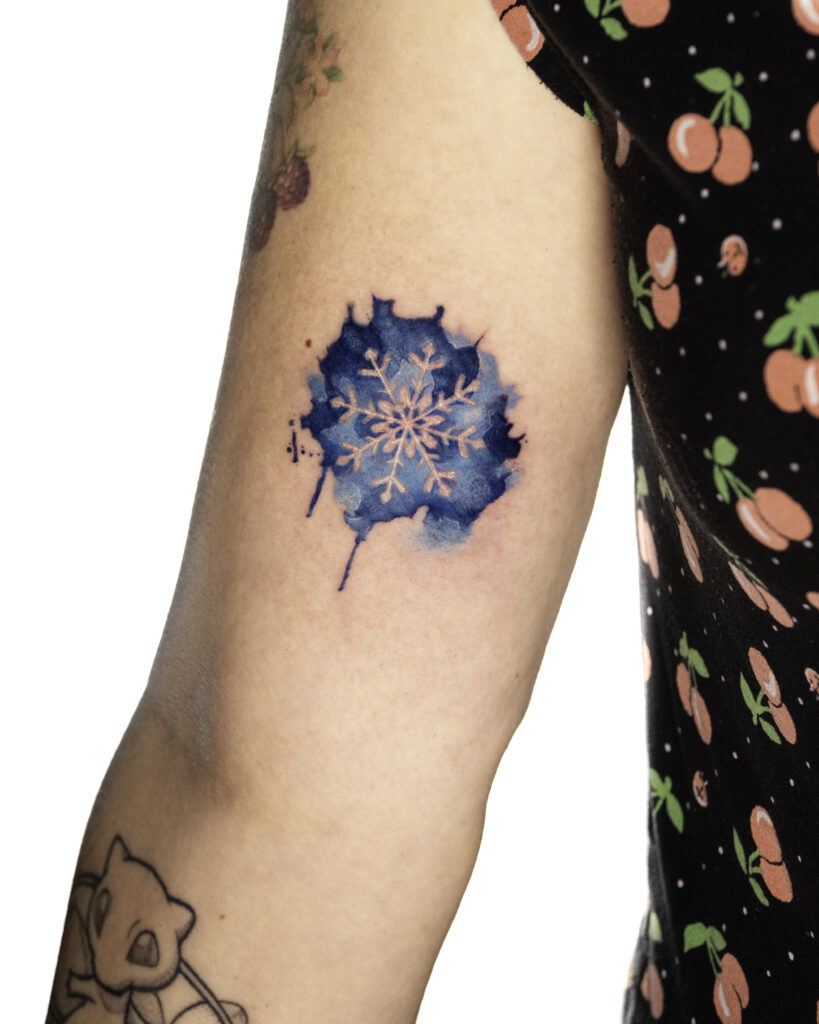 Watercolor Blue Snowflake Tattoo placed on upper arm.